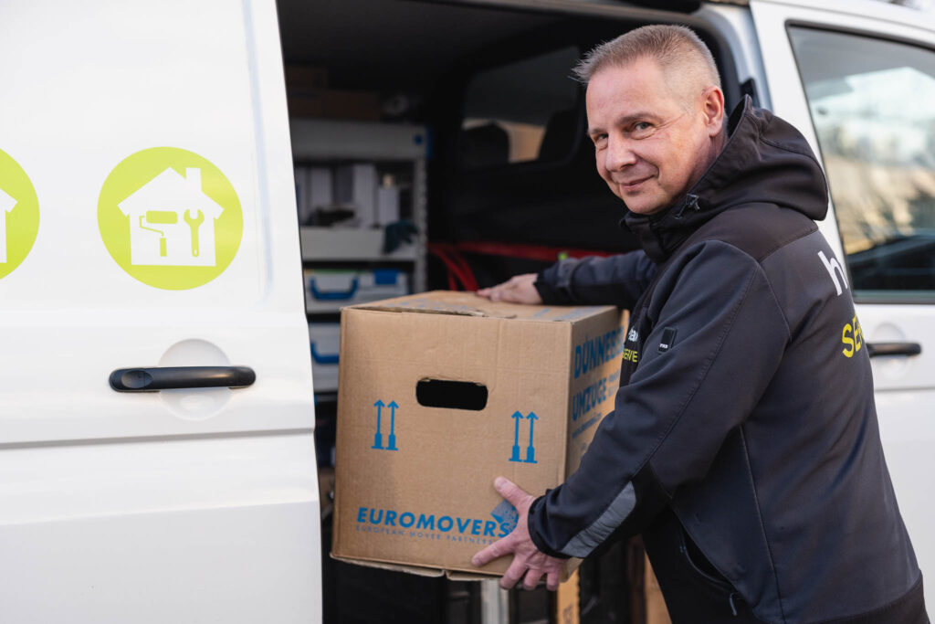 hanova SERVICES Mitarbeiter lädt Kartons in ein Auto ein