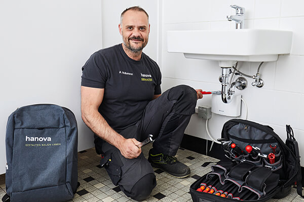 Mitarbeiter hanova SERVICES repariert ein Waschbecken